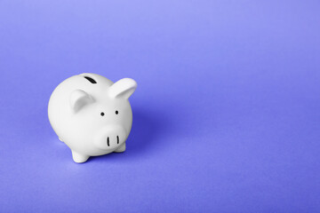 Ceramic piggy bank on purple background, space for text. Financial savings