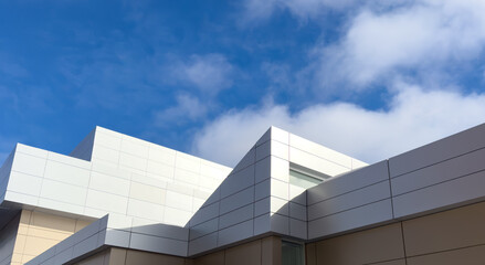 Fototapeta premium The exterior wall of a grey contemporary commercial style building with aluminum metal composite panels and glass windows. The futuristic building has engineered diagonal cladding steel frame panels.