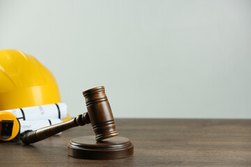 Construction and land law concepts. Gavel, hard hat, drawings and measuring tape on wooden table,...