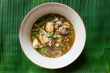 Spicy frog Soup (Tom Yum kob) hot and spicy favorite Thai food in a bowl on a green banana leaf.