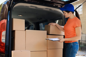 Courier counting packages near delivery truck outdoors