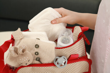 Woman putting diaper into mother`s bag, closeup