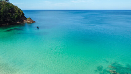 Fototapeta premium Aerial view of traditional longtail boat approaching a beach, Phuket, Thailand. Beautiful view from above. Turquoise waters of Andaman Sea on sunny day, Southeast Asia. 
