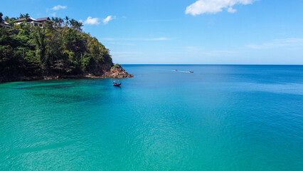 Fototapeta premium Aerial view of traditional longtail boat approaching a beach, Phuket, Thailand. Beautiful view from above. Turquoise waters of Andaman Sea on sunny day, Southeast Asia. 