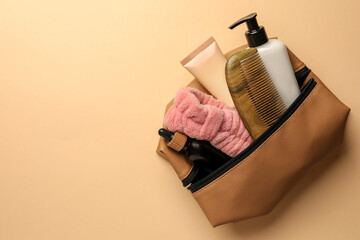 Preparation for spa. Compact toiletry bag with different cosmetic products on beige background, top...