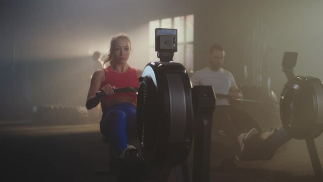 Slow-motion shot of a female athlete giving high five with her personal trainer after successful training on rowing machine