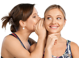 Two happy young girl friends talking or whispering, isolated on white background