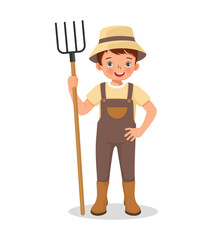 Cute little boy farmer holding a rake working in the farm