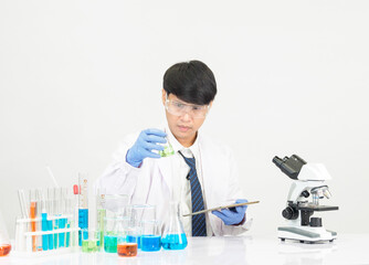 Asian male student scientist Wearing a doctor's gown in the lab looking at the chemist. caused by...