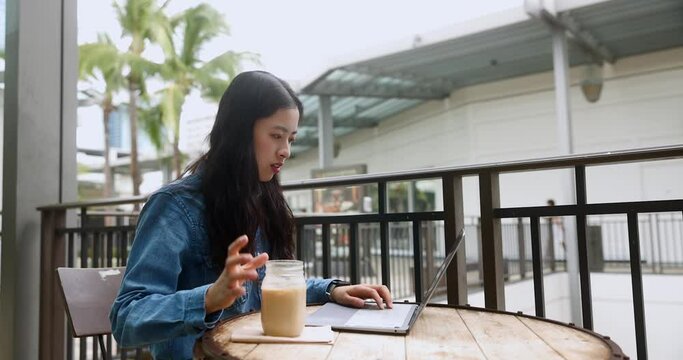 Portrait of a cute asian student girl coding IT laptop outdoors cafe and drinking a cup of coffee