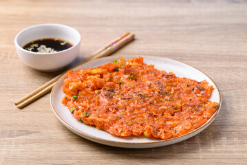 Kimchi pancake (Kimchi jeon or kimchi buchimgae) on plate eating with soy dipping sauce, Korean food
