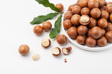 a dish of macadamia nuts with leaves. top view.