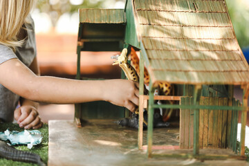 Preschool child playing with jungle animal toy set outdoors at kindergarten