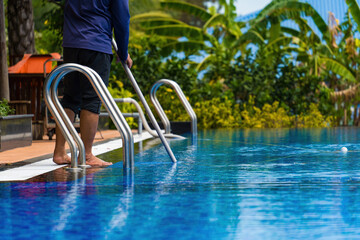 A man is doing swimming pool cleaning service. Selective focus