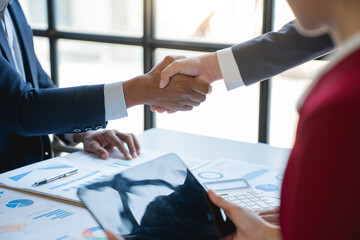 Two confident young Asian businessmen shaking hands during a meeting in office financial co-investment perfect management succeed in the office partner concept.