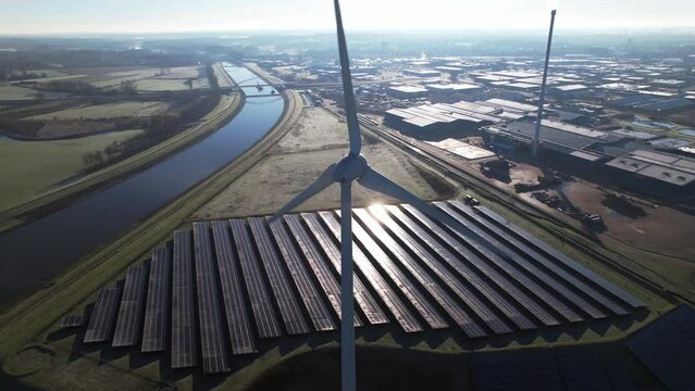 Reflection on solar panels with windmill turbine in the foreground and bio mass and water cleaning facility in The Netherlands part of sustainable industry aerial circular economy concept.