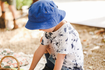 Little preschool boy wearing blue sun hat playing in beautiful tropical kindergarten garden