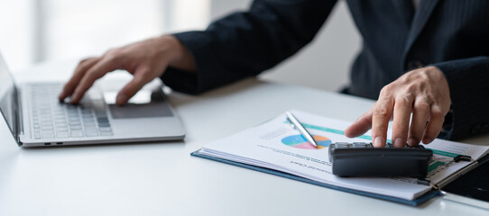 Young Asian businessman examining chart analyzing documents Financial data graph showing investment income in real estate business in office accounting management concept.