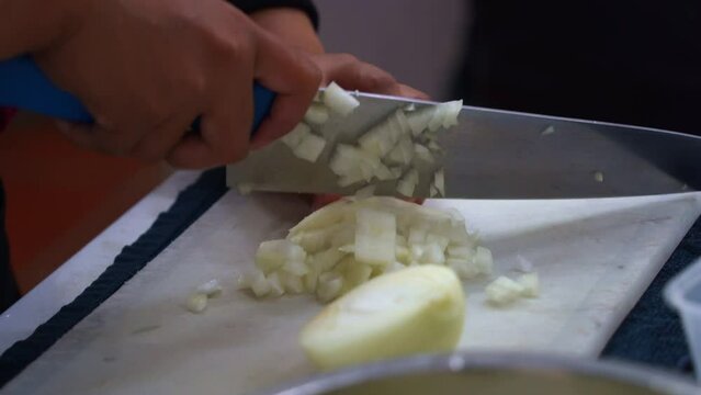 Professional kitchen hand preparing the ingredients for restaurant operation, brunoise cut the onion, close up shot.