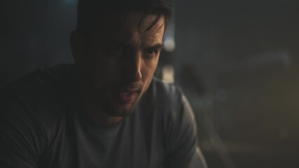 Close-up shot of a tired young man breathing heavily after doing kettelbell lifting exercise while group of people exercising in blurry background - Powered by Adobe