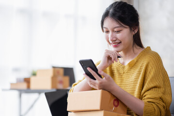 Obraz na płótnie Canvas Portrait of Online business owner Asian female small businesses SME entrepreneur working at home, online marketing, packing boxes, SME sellers, concept, e-commerce team, online sales.