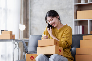 Fototapeta na wymiar Portrait of Online business owner Asian female small businesses SME entrepreneur working at home, online marketing, packing boxes, SME sellers, concept, e-commerce team, online sales.