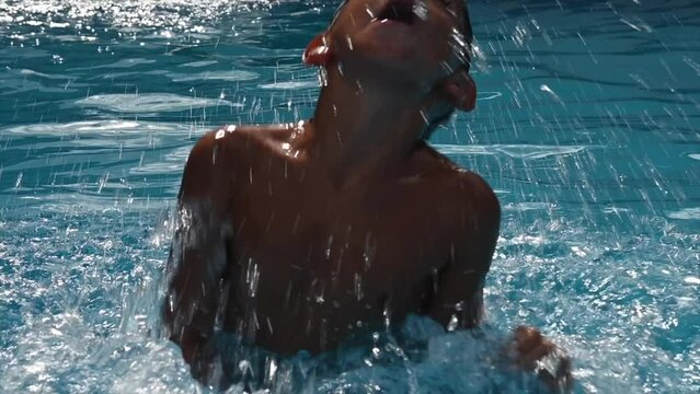 happy child comes out of the water in the pool in slow motion in summer
