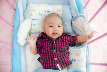 Top view of asian cute baby boy lying in his crib