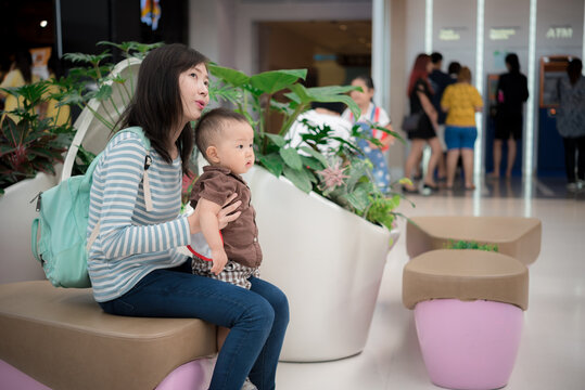 Young asian mother and daugther baby sitting on sofa in the mall for relax