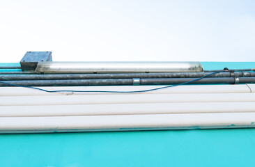 Old Air conditioner duct white plastic wiring  Installed on wall of blue building with neon bulbs....