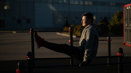 Young caucasian man doing parallel bars exercise outdoors. 