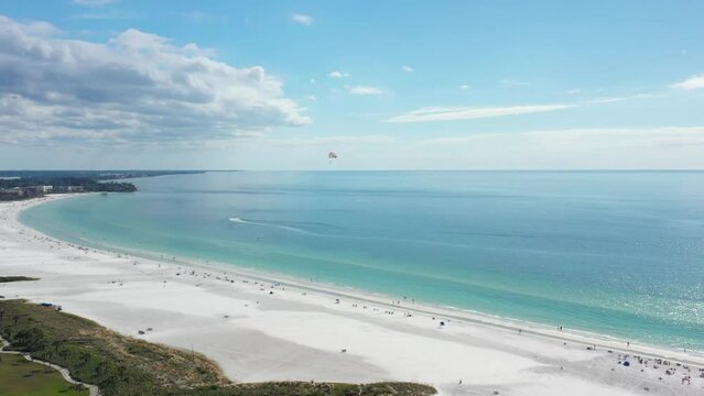 Aerial view of Siesta Key beach with white sand and turquoise water, paraglider flying above the beach