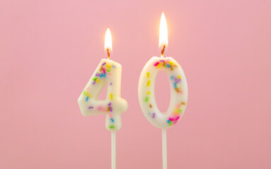 White decorated burning birthday candles on pink background, number 40