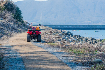 All terrain vehicle parked on path to dock at small ocean harbor.