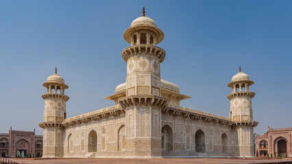 Fototapeta na wymiar Beautiful symmetrical marble tomb of Itmad-Ud-Daulah on a blue sky background. Mausoleum with minarets, domes, arches. The walls are decorated with ornaments, inlays of precious stones. India. Agra.