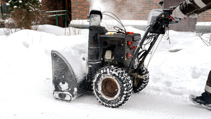 snowblower removes snow, a man cleans the yard outside