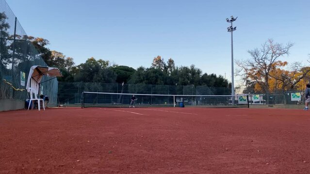 WIDE SIDE VIEW Young Caucasian teenager female tennis player serving during a game or practice.
