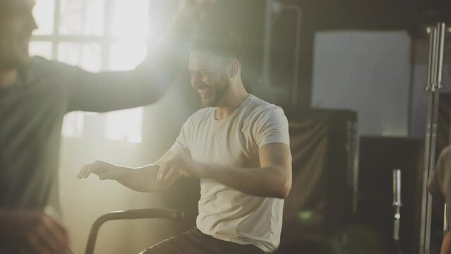 A group of four friends talking and smiling after a successful training session with stationary bike. Giving high five with each other after workout session