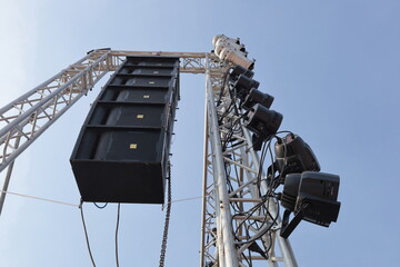 Black speakers hang on a metal frame. Speaker set hanging on silver metal frame with par lights...