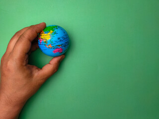 Hand holding earth globe on a green background