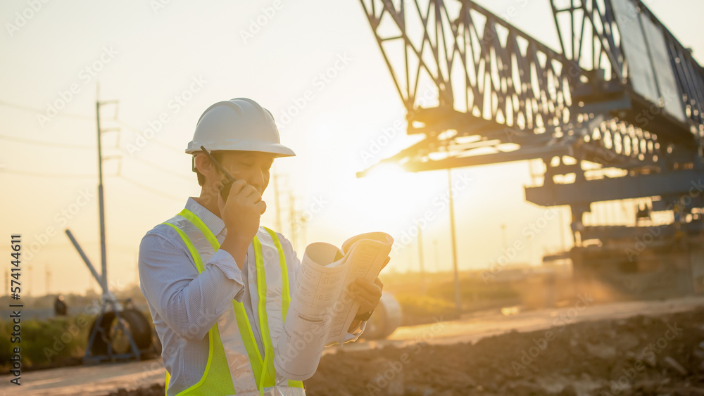Poster men engineer talking on walkie-talkie and holding blueprint for inspecting and working at constructi
