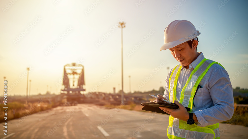 Poster asian engineer with hardhat using tablet pc computer inspecting and working at construction site