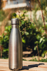 Water bottle. Reusable steel thermo water bottle on wooden bench. Sustainable lifestyle. Plastic...