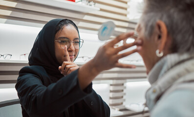 Optometry, vision and eye test with an islamic woman optician working to diagnose a customer....