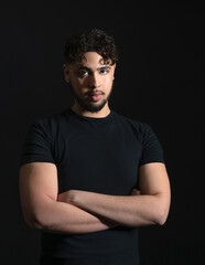 Intense focused interracial young man in black t shirt staring at camera isolate on black background - 574151019