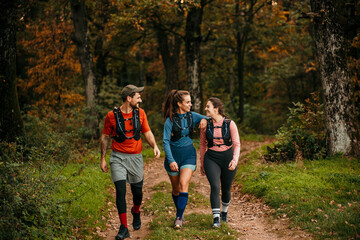 Young male and female embraced joggers walking and resting after running in the forest.