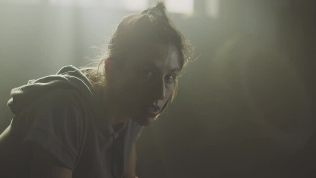 Beautiful sweaty athletic woman sitting at gym and smiling while looking at camera