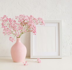 Frame mockup with copy space for artwork, photo, painting, print presentation and pink  modern vase with pink flowers near white wall .Minimal scandinavian interior design.
