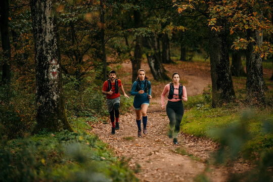 Young male and female joggers running in the forest. Cropped shot of a group of friends jogging in the wood