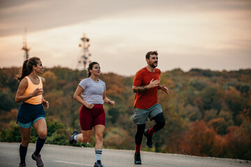 A small group of focused athletes enjoying running and communicating while jogging in nature.